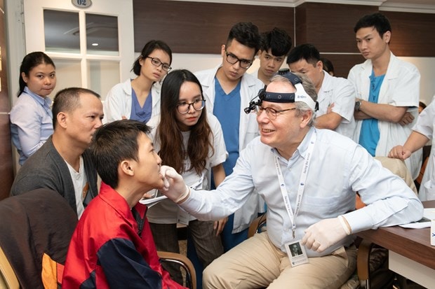 Bác sỹ của tổ chức Facing the World khám cho bệnh nhân bị dị tật. (Ảnh: PV/Vietnam+)