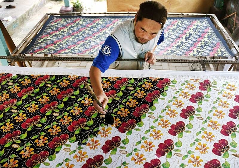 Một nghệ nhân batik vẽ các mẫu táo bằng cách sử dụng thuốc nhuộm hữu cơ ở Batu, Đông Java của Indonesia. Ảnh: Jakartapost