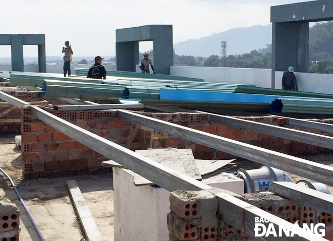 Công nhân đang thi công lợp mái tôn tại tòa nhà E1, dự kiến hoàn thành vào ngày 24-11.