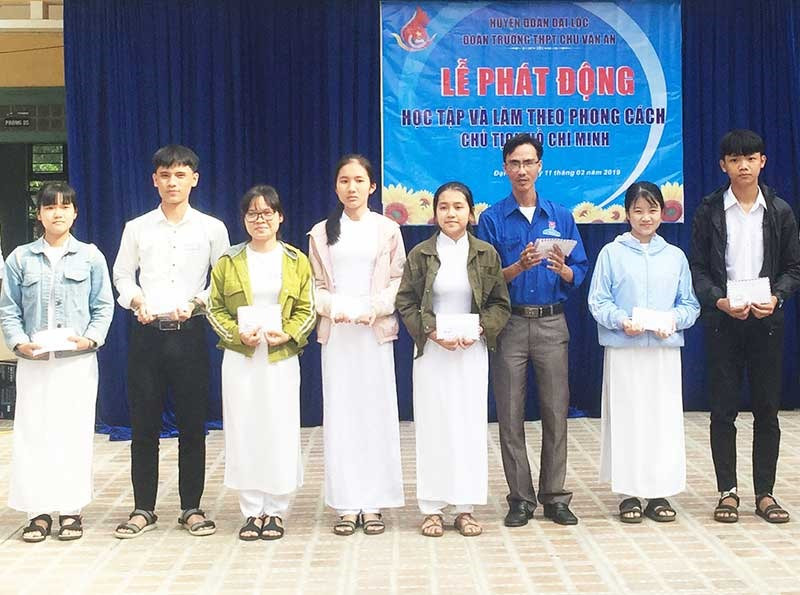 Thầy giáo Trần Minh Giang (áo xanh ở giữa) tặng quà cho các em học sinh - Ảnh: THÁI CƯỜNG