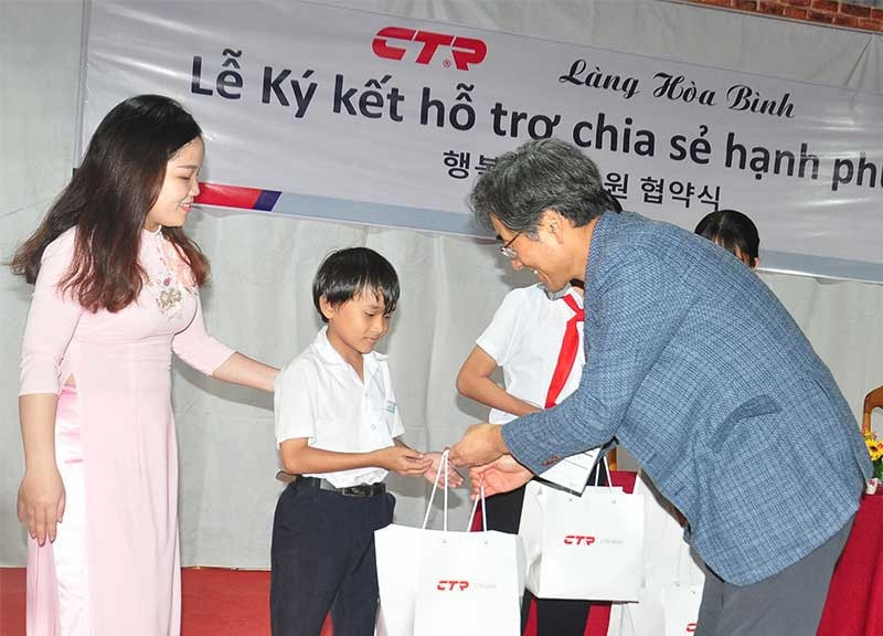 Lãnh đạo Công ty CTR Vina tặng quà học sinh Làng Hòa Bình. Ảnh: VINH ANH