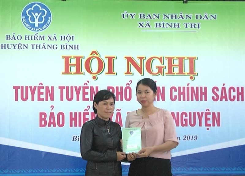 Bà Trần Thị Thu Hồng - Giám đốc BHXH huyện Thăng Bình (phải) trao sổ BHXH tự nguyện cho bà Nguyễn Thị Thao (xã Bình Trị). Ảnh: Biên Thực