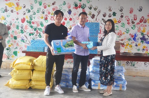 HLV Vũ Hồng Việt (giữa) và cầu thủ Đinh Thanh Trung trao quà cho Làng Hòa Bình. Ảnh: T.V