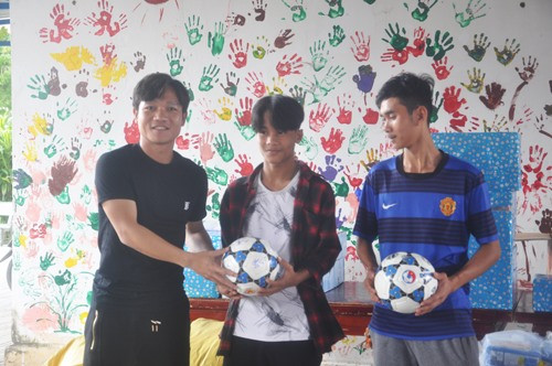 Đội trưởng Đinh Thanh Trung tặng 2 quả bóng cho các em Làng Hòa Bình. Ảnh: T.V