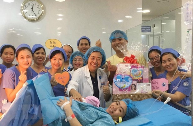 Ban giám đốc, êkíp trực đêm tại Bệnh viện Từ Dũ tặng quà cho sản phụ sinh con đầu tiên trong năm 2020. (Ảnh: Đinh Hằng/TTXVN)