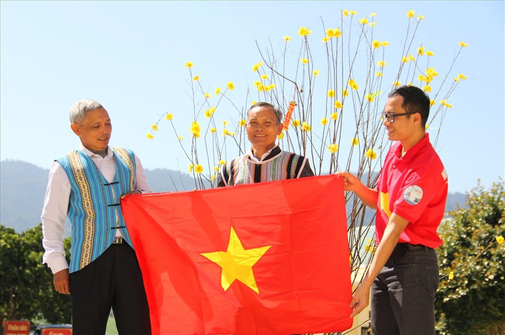 Nhà báo Trần Thường (bên phải) trao cờ Tổ quốc cho đại diện già làng uy tín ở xã Đắc Pring (huyện Nam Giang). Ảnh: Đ.N