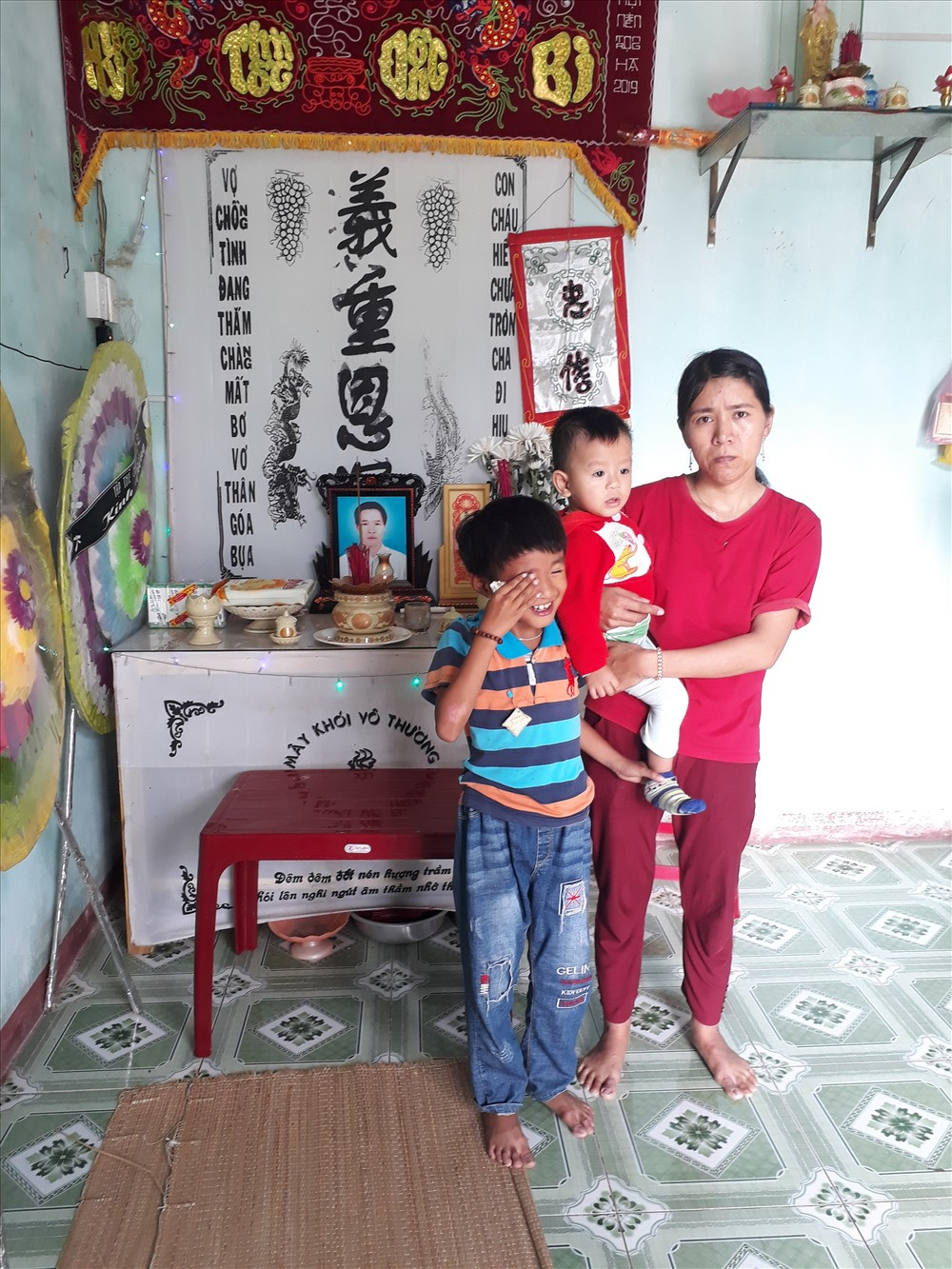 Chị Hạnh và 2 đứa con thơ cạnh di ảnh của chồng.Ảnh: C.P