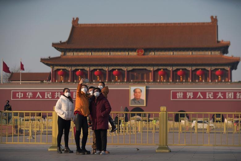 Du khách đeo khẩu trang chụp ảnh selfie trước cổng Thiên An Môn ở Bắc Kinh ngày 30/1.