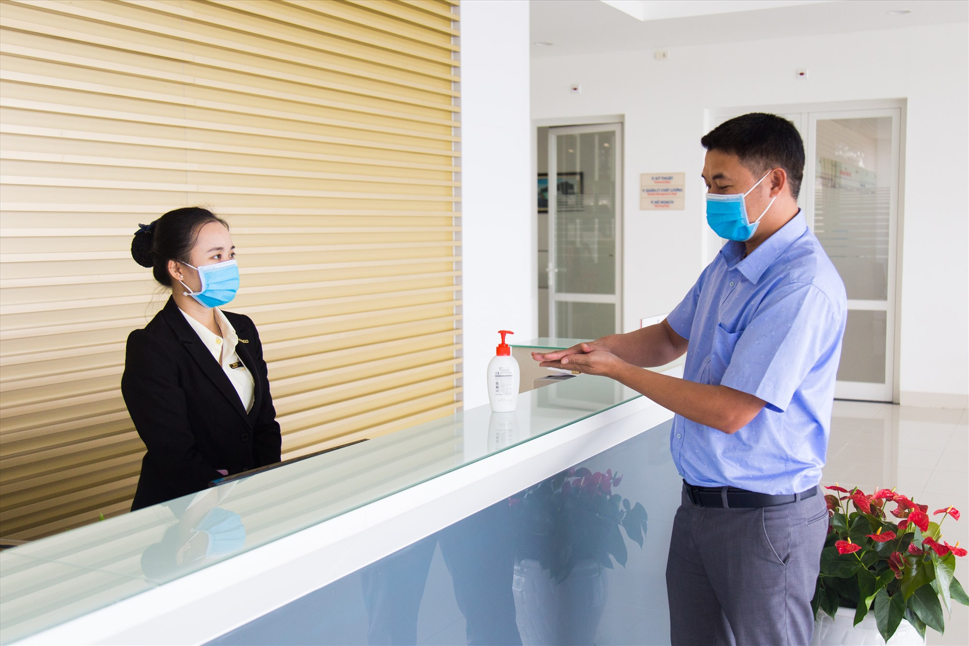 Nhân viên Lễ tân NM THACO Bus hướng dẫn khách rửa tay bằng cồn sát khuẩn khi làm việc tại nhà máy