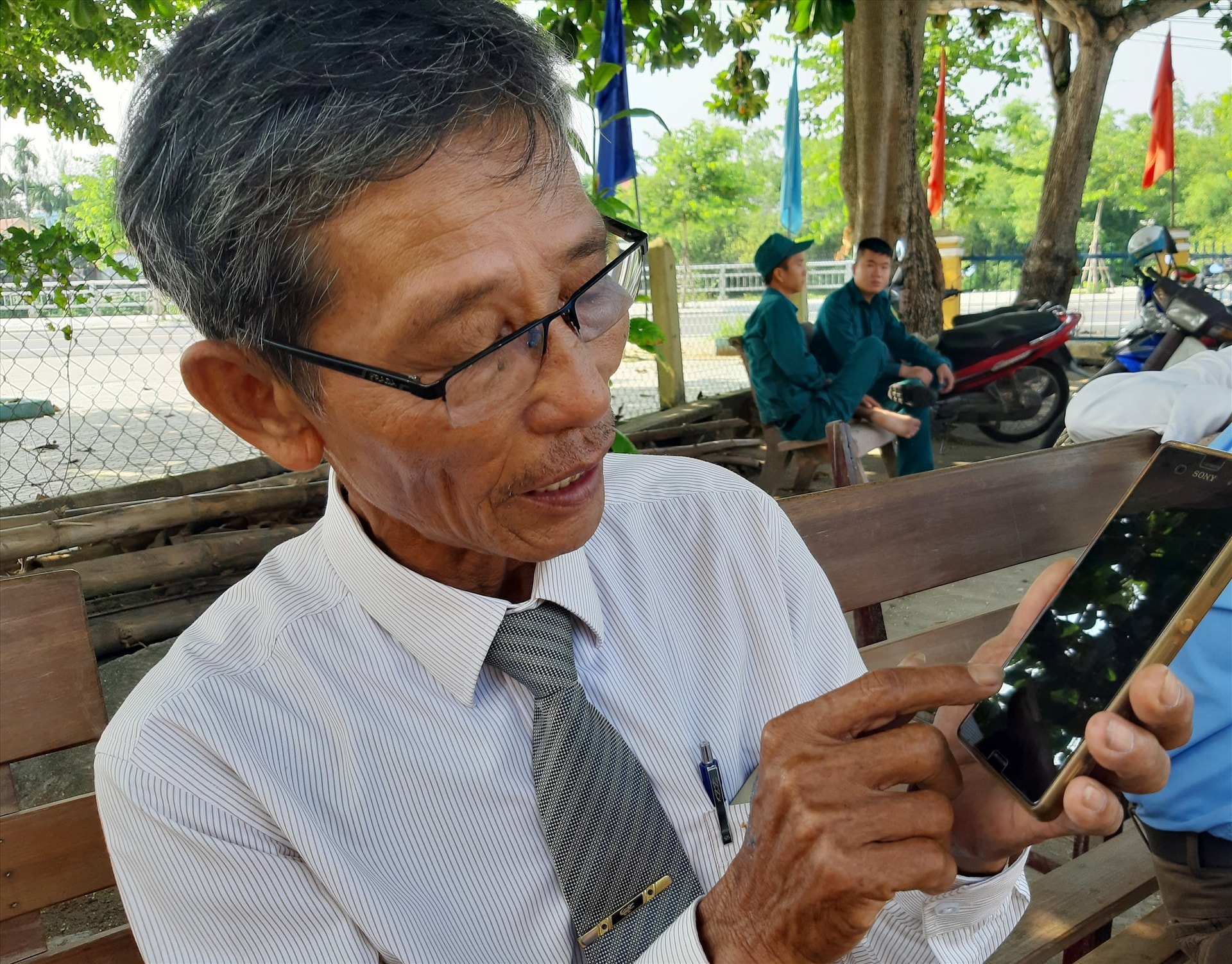 Ông Nguyễn Viết Đãi - Bí thư Chi bộ khối phố An Bang cùng chiếc điện thoại thông minh ứng dụng vào công việc. Ảnh: L.H