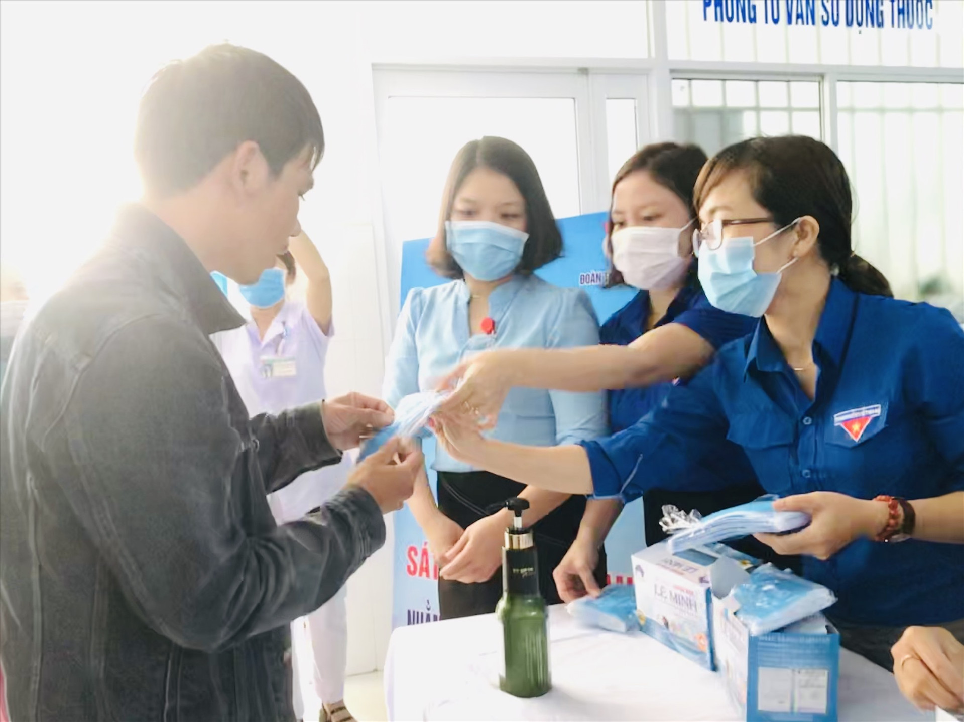 Đoàn viên thanh niên BVĐK Quảng Nam phát và hướng dẫn đeo khẩu trang đúng cách tại Khoa khám bệnh. Ảnh: C.N