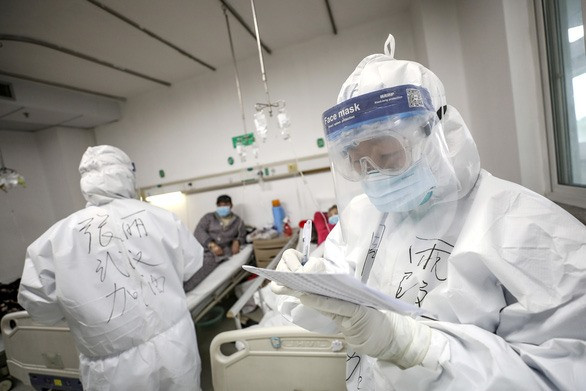 Một nhân viên y tế mặc đồ bảo hộ kiểm tra bệnh án của người bệnh tại bệnh viện Kim Ngân Đàm ở Vũ Hán, tỉnh Hồ Bắc, Trung Quốc ngày 13-2-2020 - Ảnh: REUTERS