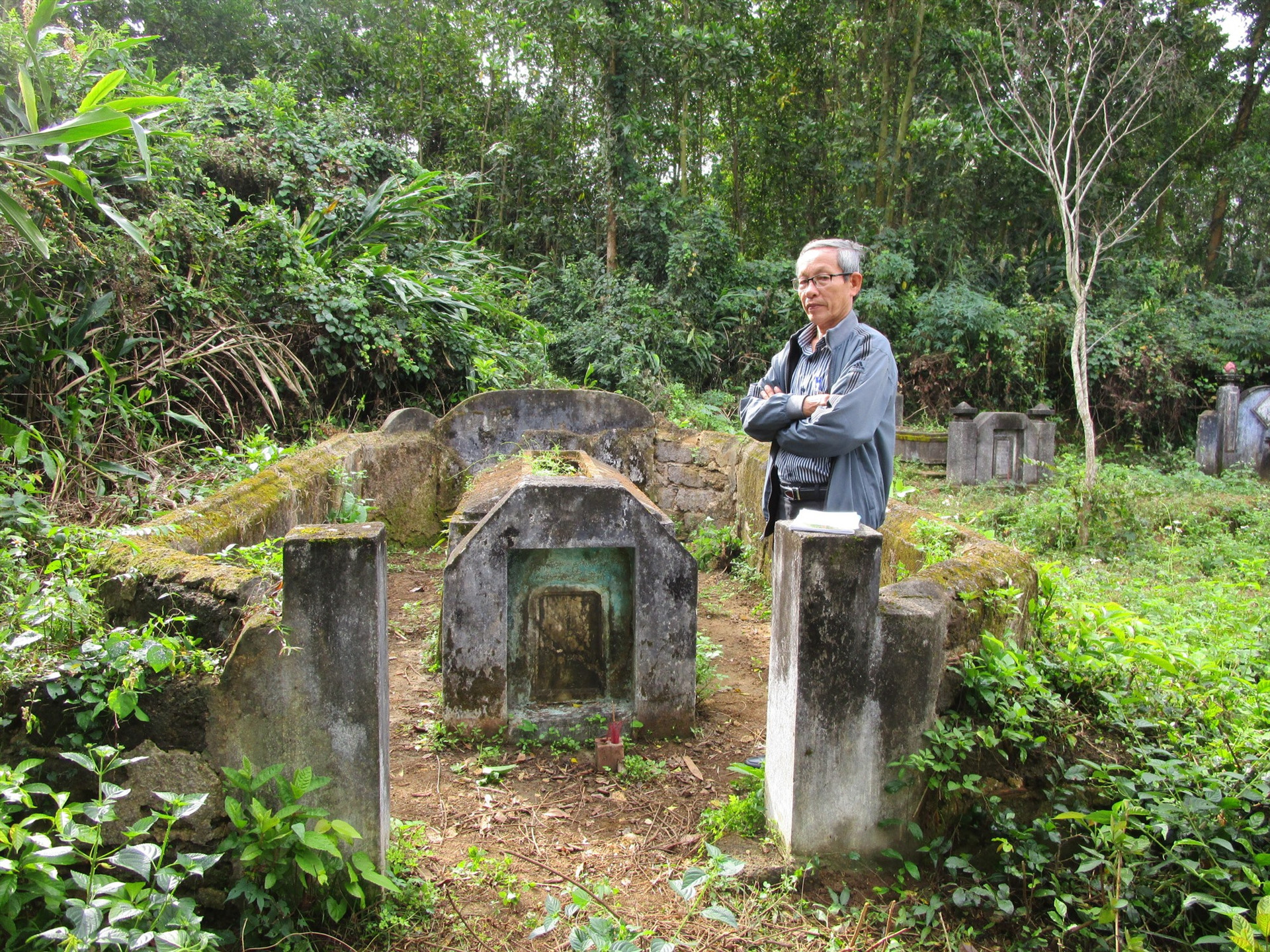 Thầy giáo hưu trí Hồ Nhật Tiến bên mộ ông tam khoa tú tài Hồ Phổ. Ảnh: PHÚ BÌNH