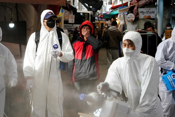 Nhân viên khử trùng một khu chợ truyền thống ở Seoul, Hàn Quốc, ngày 26-2 - Ảnh: REUTERS