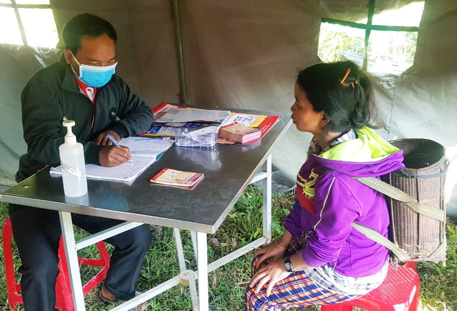 Bác sĩ Clâu Hín kiểm tra lịch trình của một phụ nữ Lào đến khám sức khỏe tại trạm kiểm soát. Ảnh: THÔNG NGUYỄN