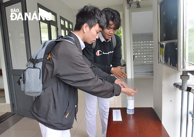 Học sinh lớp 12 Trường THPT Phan Châu Trinh tự giác xác khuẩn trước khi vào lớp học. Ảnh: NGỌC PHÚ