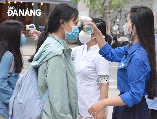 Học sinh lớp 12 Trường THPT Trần Phú được Đoàn viên Thanh niên Nhà trường đo thân nhiệt trước khi vào lớp. Ảnh: NGỌC PHÚ