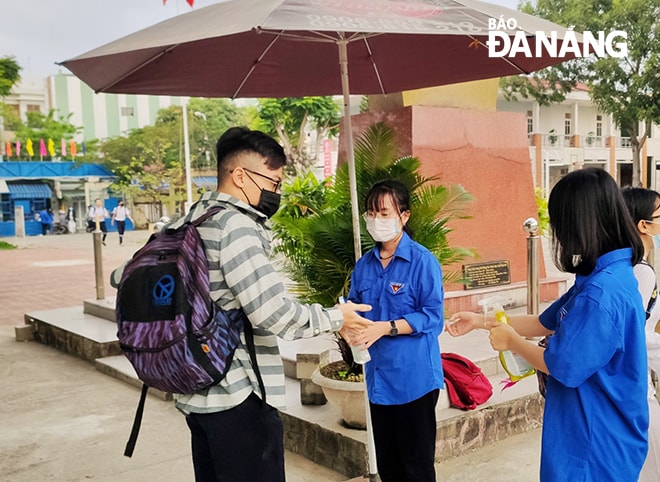 Đoàn viên Trường THPT Hoàng Hoa Thám tiến hành sát khuẩn cho học sinh trước khi vào lớp. Ảnh: NGỌC PHÚ