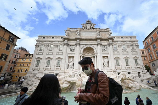 Du khách mang khẩu trang phía trước đài phun nước Trevi tại thành phố Rome của Ý. Người dân Ý trước đây không có thói quen mang khẩu trang khi đi lại trên đường phố. Ảnh: AFP/Getty Images