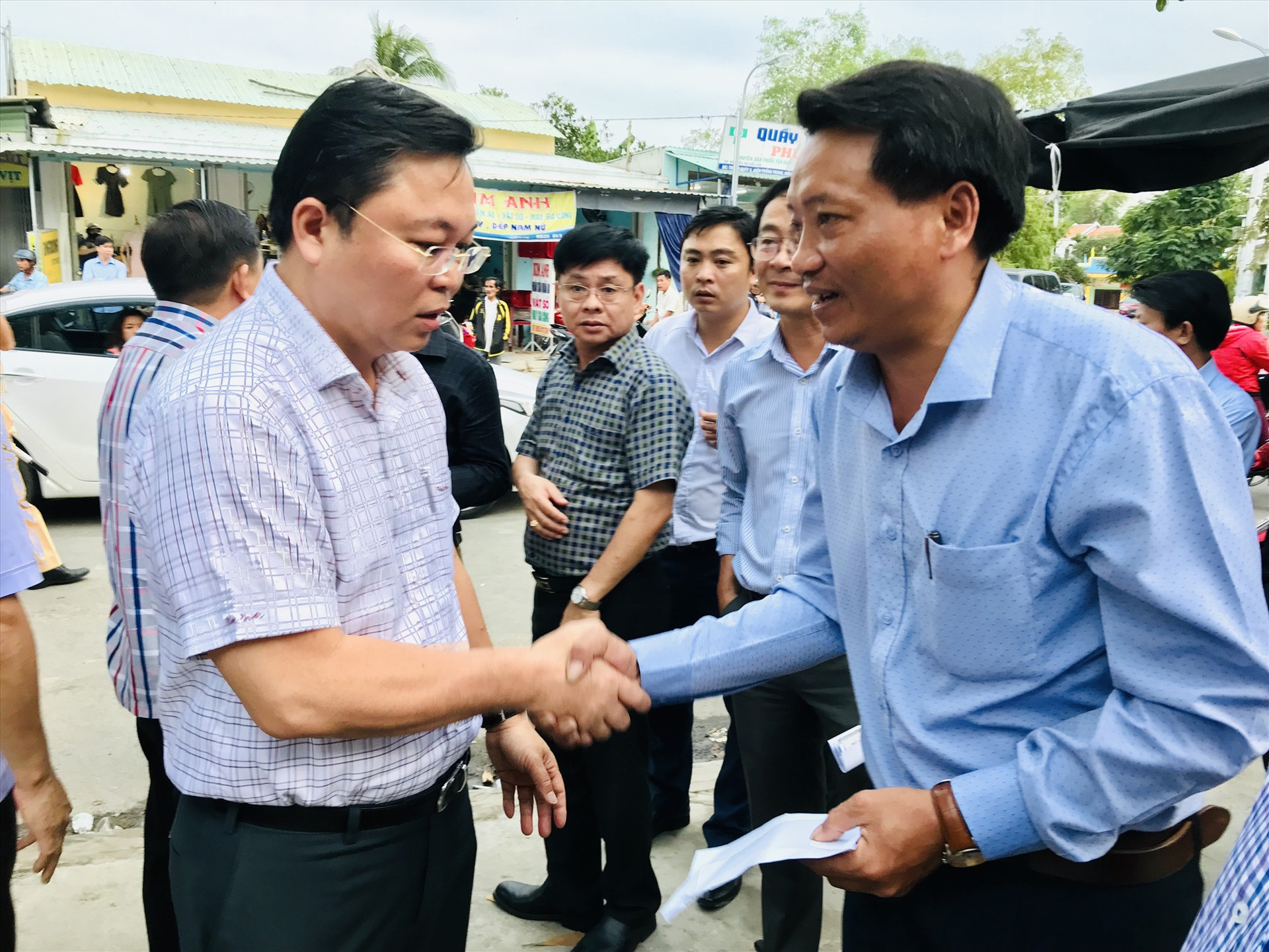 Chủ tịch UBND tỉnh Lê Trí Thanh trao quà động viên tiểu thương cho đại diện lãnh đạo xã Điện Thắng Trung. Ảnh: Q.T