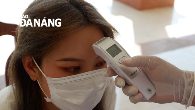 Mỗi ngày các công dân được kiểm tra thân nhiệt 2 lần để nhận biết dấu hiệu nếu nhiễm bệnh. Ảnh: PHAN CHUNG
