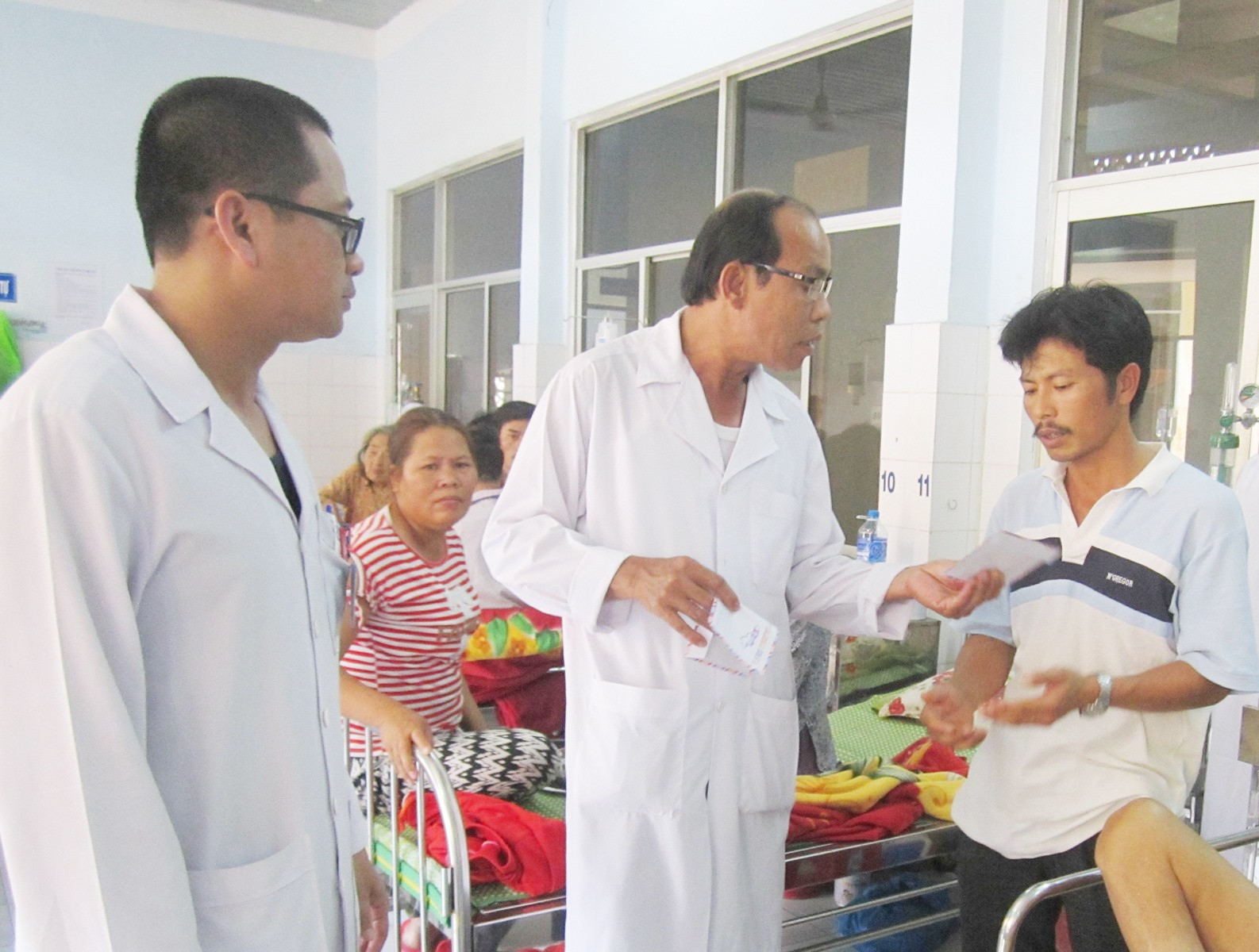 Bác sĩ Trần Phước Ta trao tiền hỗ trợ bệnh nhân nghèo. Ảnh: N.TRANG