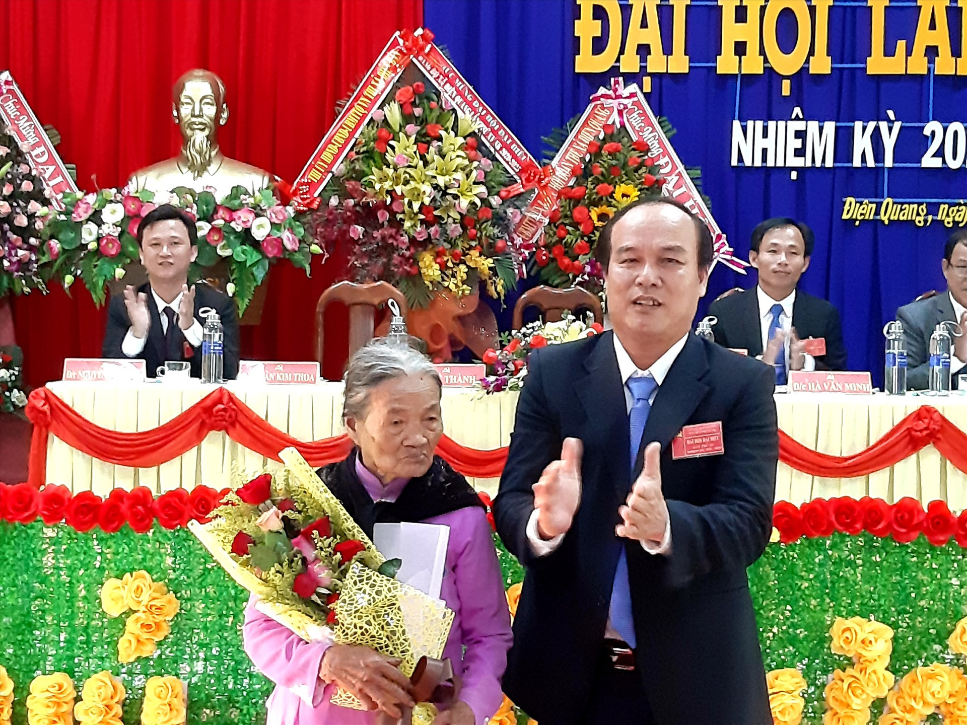 Ông Lê Thành - Bí thư Đảng ủy xã Điện Quang (khóa XIV) tặng quà và hoa cho Bà mẹ Việt Nam anh hùng Phạm Thị Hân tại phiên khai mạc Đại hội. Ảnh: VĂN SỰ