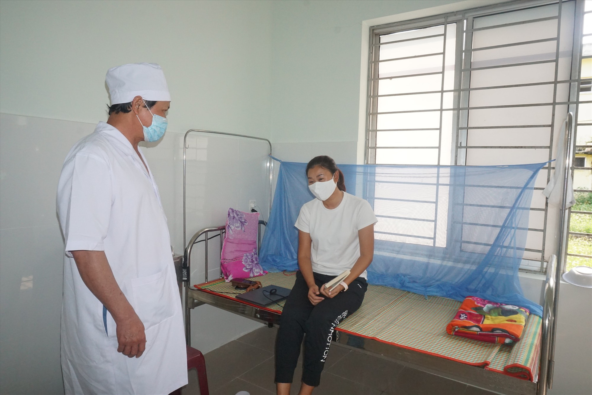 Cán bộ Trung tâm Y tế huyện Thăng Bình thăm hỏi người thực hiện cách ly tại Khoa Truyền nhiễm. Ảnh: T.THỰC