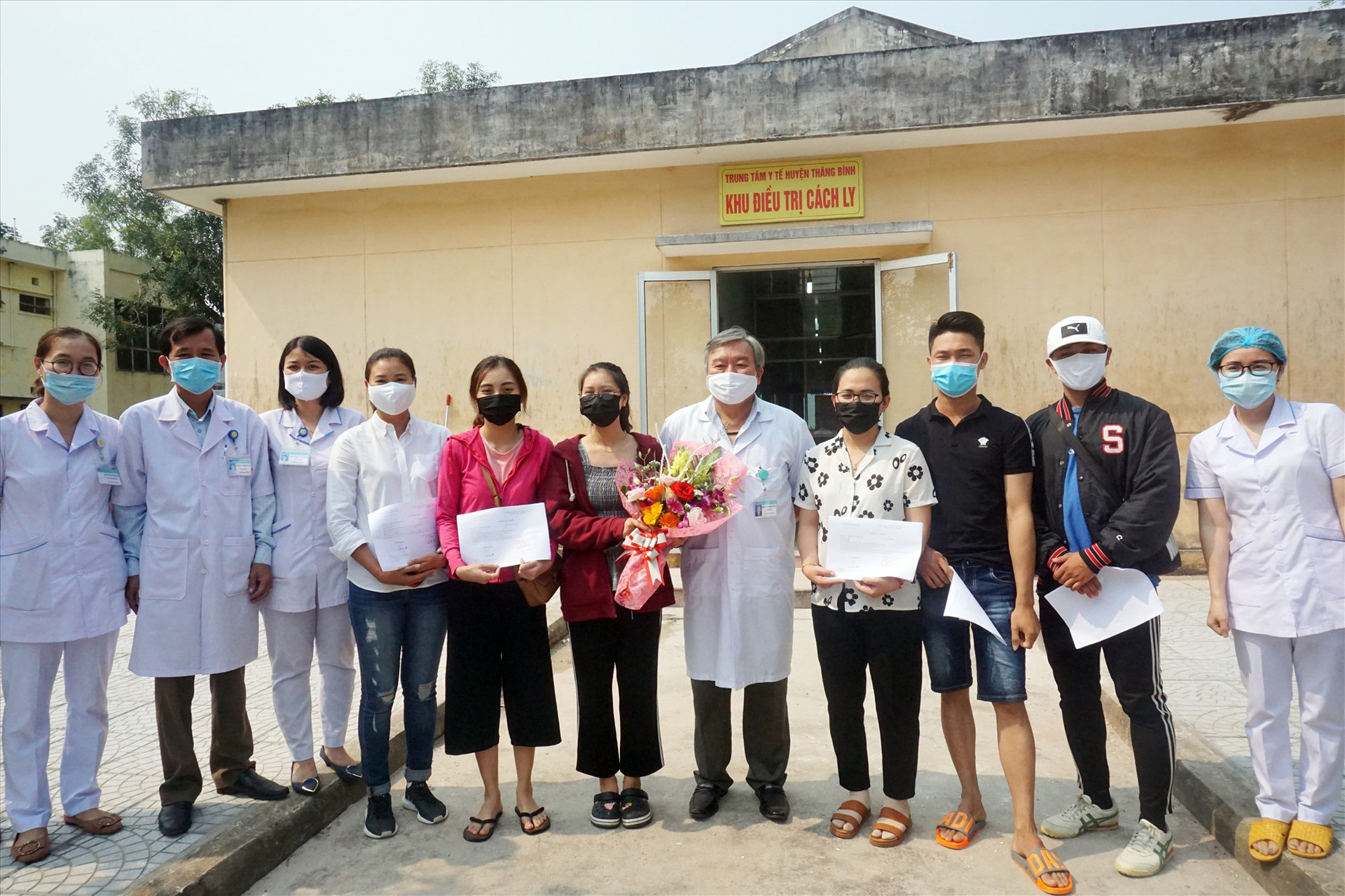 Đại diện Trung tâm Y tế huyện Thăng Bình trao hoa và giấy xác nhận hoàn thành cách ly y tế cho 6 trường hợp cách ly tại đây. Ảnh: BIÊN THỰC