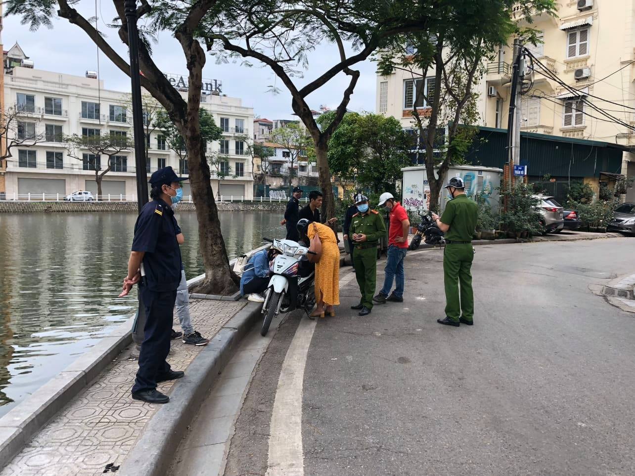 Lực lượng chức năng xử lý một phụ nữ không đeo khẩu trang trong sáng 28-3 trên phố Trúc Bạch.