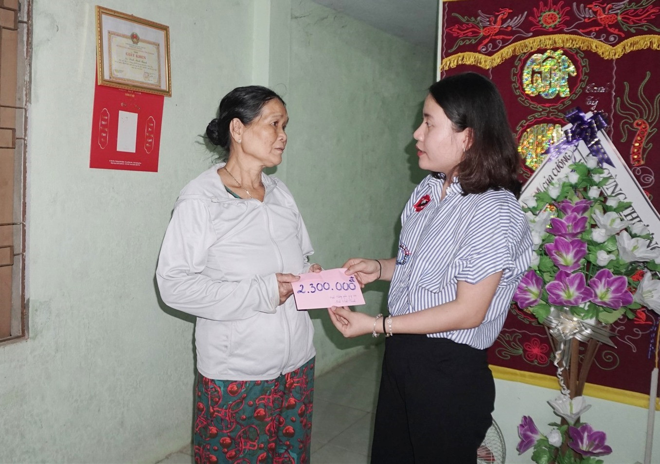 Đại diện gia đình nhận số tiền 2,3 triệu đồng bạn đọc giúp đỡ em Đinh Minh Thạnh. (ảnh: NT)