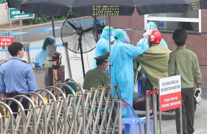 Nhân viên y tế kiểm tra thân nhiệt người vào viện trong chiều 28-3. Ảnh: Thanh Tùng/TTXVN