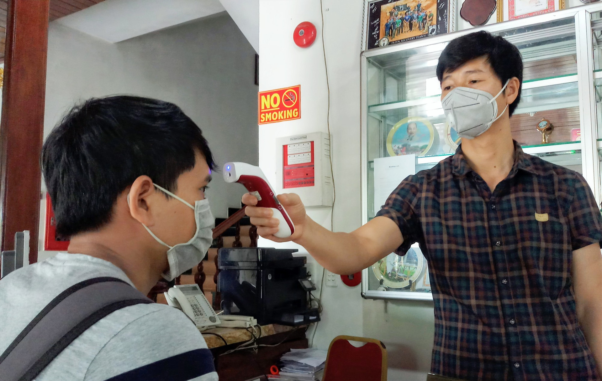 Nhân viên khách sạn Bé Châu Giang (Phước Sơn) tiến hành đo thân nhiệt khách đến đặt phòng lưu trú. Ảnh: ALĂNG NGƯỚC
