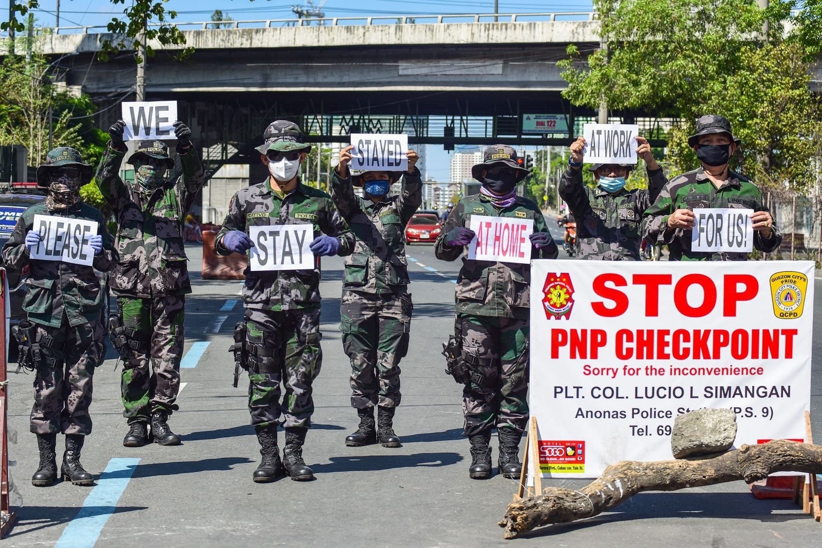 Cảnh sát giơ cao biển nhắc nhở người dân hãy ở trong nhà để phòng lây lan Covid-19 tại Manila, Philippines. Ảnh: AFP/TTXVN