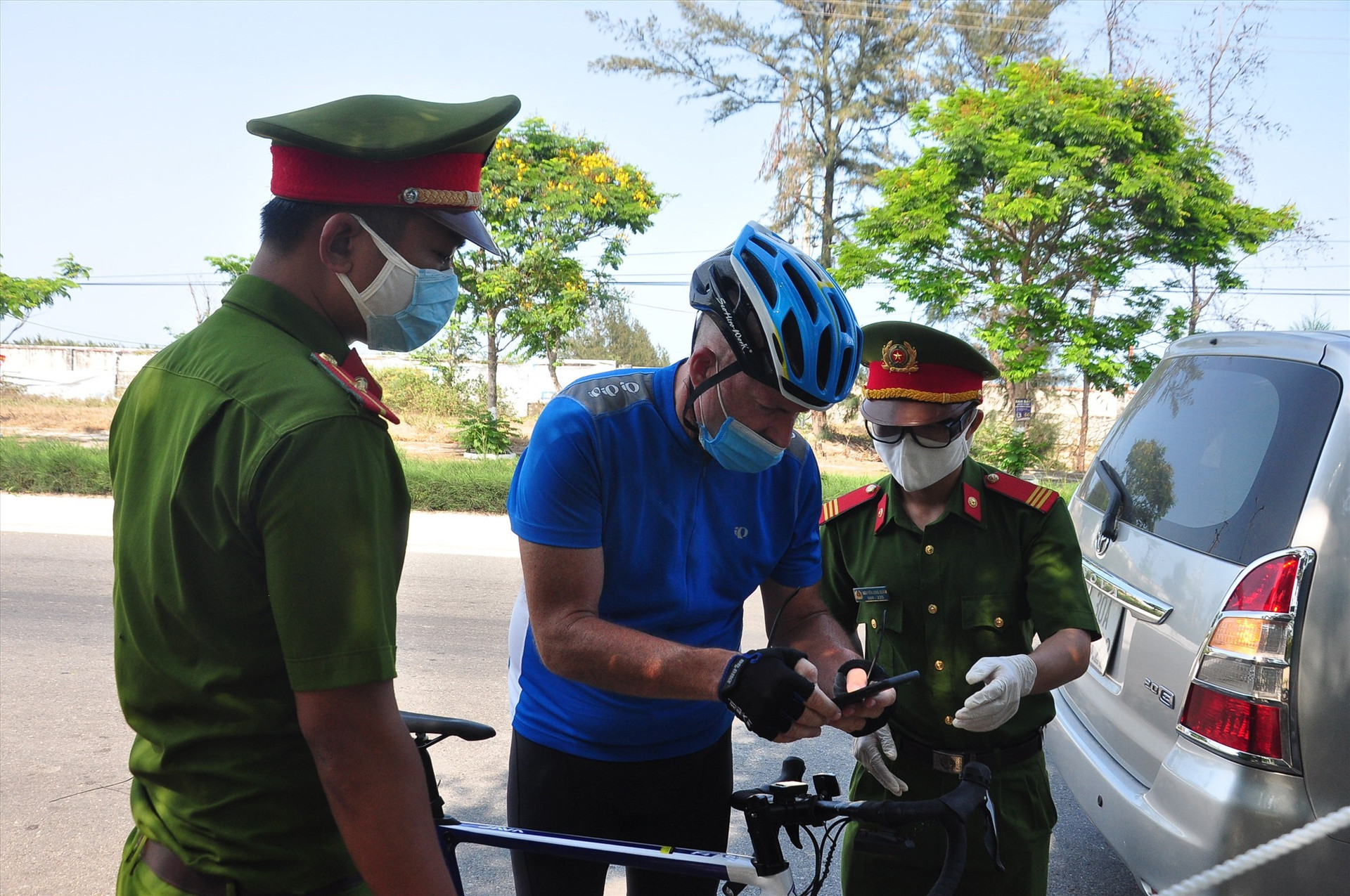 Tại chốt kiểm soát phía bắc trên đường ĐT603B, lực lượng làm nhiệm vụ đang kiểm tra một người ngoại quốc lưu thông bằng xe đạp từ hướng Đà Nẵng vào Hội An. Ảnh: V.A
