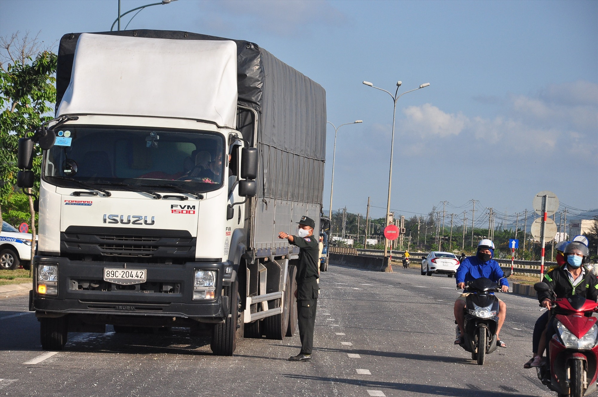 Giữa cái nắng chói chang, một chiến sĩ cảnh sát cơ động đang hướng dẫn tài xế xe tải chấp hành việc kiểm soát dịch bệnh Covid-19 tại chốt kiểm soát phía nam. Ảnh: V.A