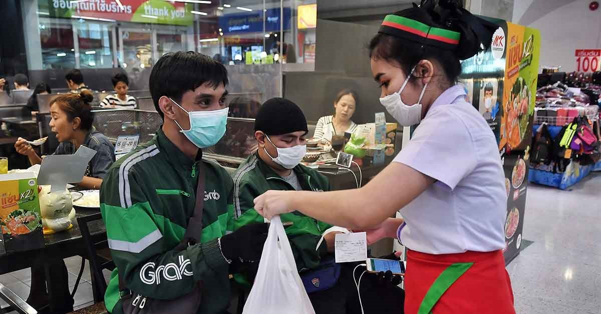 Các tài xế Grab nhận đồ ăn tại một quầy hàng để giao cho khách hàng tại Băng Cốc, Thái Lan. Ảnh: AFP