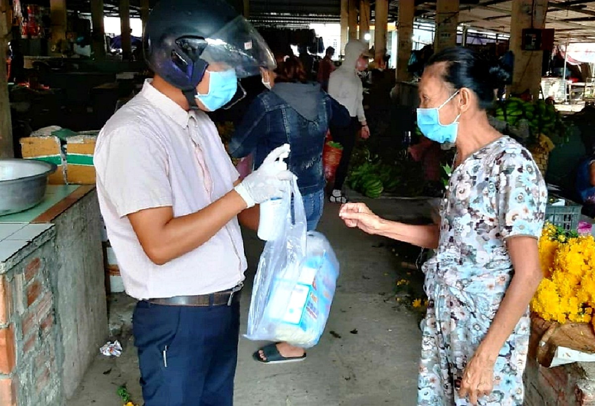 Cán bộ hội nông dân ở Duy Xuyên cấp phát dung dịch sát khuẩn cho người dân tại các chợ. Ảnh: H.N