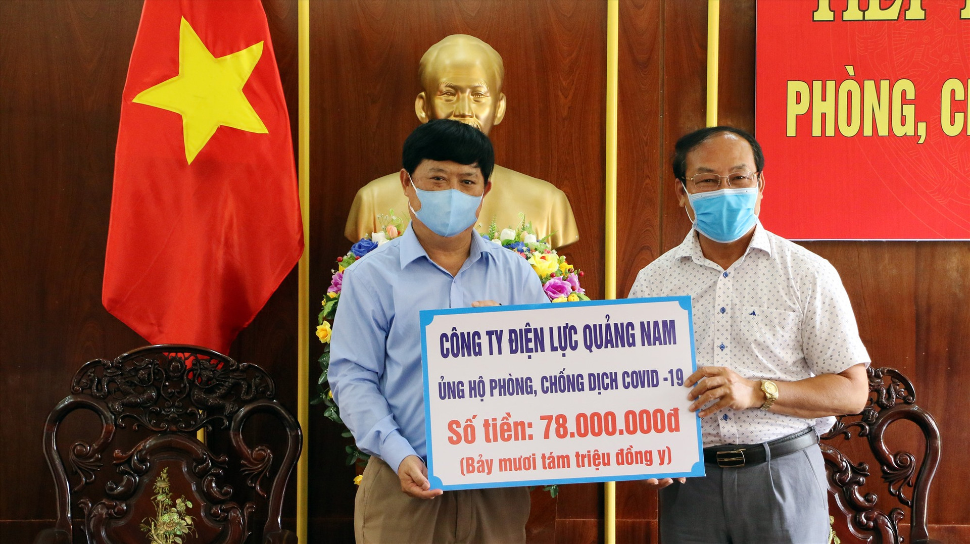 Ông Nguyễn Bê - Chủ tịch Công đoàn PC Quảng Nam (bên trái) trao biểu trưng số tiền ủng hộ.