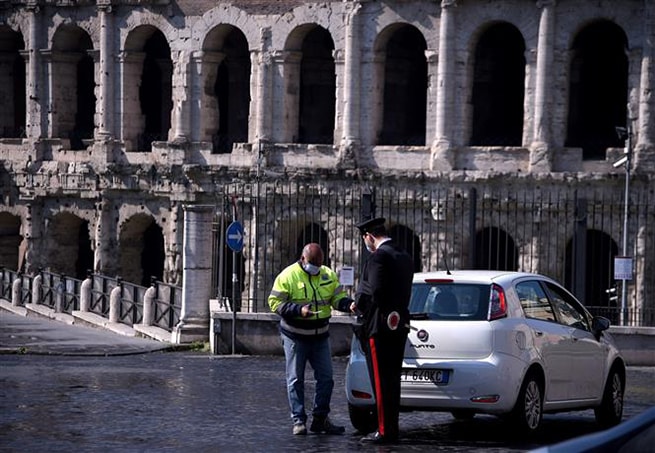 Cảnh sát Italy kiểm tra giấy tờ một lái xe tại Rome, ngày 8-4-2020 khi lệnh phong tỏa toàn quốc được thực thi nhằm ngăn dịch Covid-19. Ảnh: AFP/TTXVN
