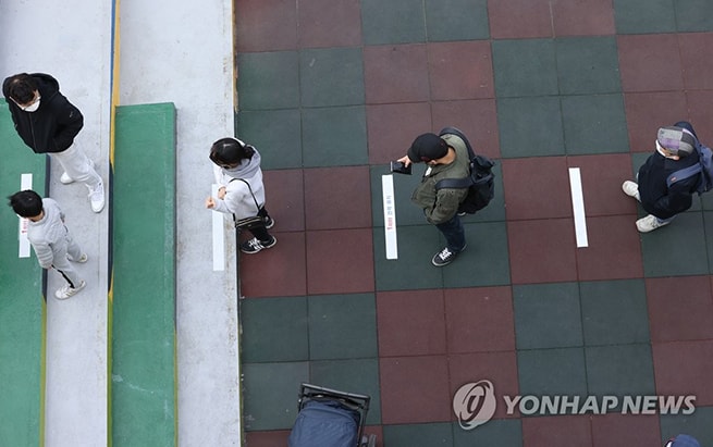 Vạch kẻ trên mặt đường giữ khoảng cách cho người đi bỏ phiếu. Ảnh: Yonhap