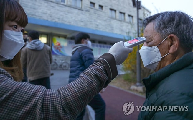 Trước khi vào bỏ phiếu, người dân được kiểm tra thân nhiệt. Ảnh: Yonhap