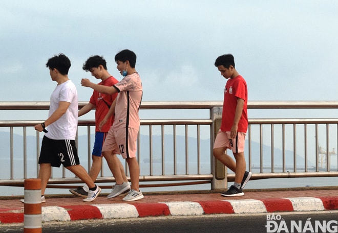 Một nhóm người đi bộ tập thể dục trên cầu Thuận Phước không đeo khẩu trang và không bảo đảm khoảng cách tối thiểu giữa 2 người (ảnh chụp lúc 6 giờ 45 sáng 12-4). Ảnh: HOÀNG HIỆP