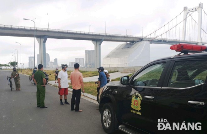 Lực lượng chức năng phường Nại Hiên Đông (quận Sơn Trà) nhắc nhở, xử lý một nhóm người tập thể dục trên đường Lê Văn Duyệt (ảnh chụp lúc 7 giờ sáng 12-4). Ảnh: HOÀNG HIỆP