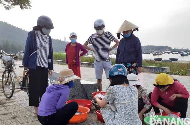 Một nhóm người đi tập thể dục tụ tập xung quanh một hộ bán hàng rong ở đường Hoàng Sa để mua cá, mực, cua... (ảnh chụp lúc 7 giờ 30 sáng 12-4). Ảnh: HOÀNG HIỆP