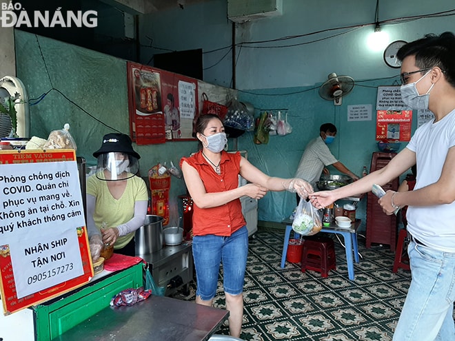 Một hộ kinh doanh ăn uống ở quận Cẩm Lệ thực hiện nghiêm việc phòng, ngừa dịch bệnh khi mở cửa vào sáng 16-4. Ảnh: KHÁNH HÒA