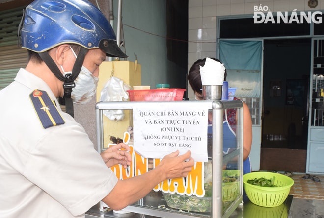 Lực lượng chức năng đến các cơ sở kinh doanh ăn uống dán thông báo chỉ phục vụ bán hàng qua mạng và bán cho khách mang về, không phục vụ tại chỗ. Ảnh: HOÀNG HIỆP
