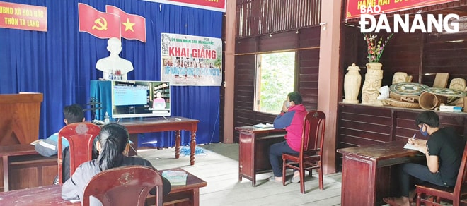 Học sinh lớp 9 thôn Tà Lang, Giàn Bí học bài mới qua truyền hình tại nhà Rông. Ảnh: NGỌC PHÚ
