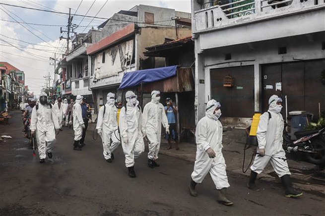 Binh sĩ và cảnh sát Indonesia phun thuốc khử trùng nhằm ngăn chặn sự lây lan của dịch Covid-19 tại Surabaya ngày 16-4-2020. Ảnh: THX/TTXVN
