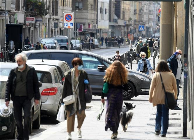 Người dân đeo khẩu trang phòng lây nhiễm Covid-19 trên đường phố tại Milan, Italy ngày 18-4-2020. Ảnh: THX- TTXVN